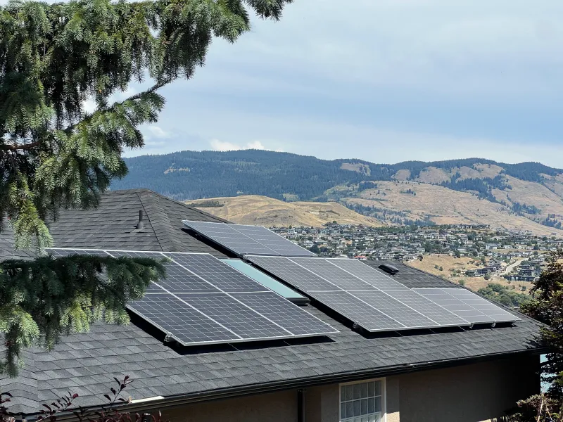 A finished array of black panels on a shingle roof