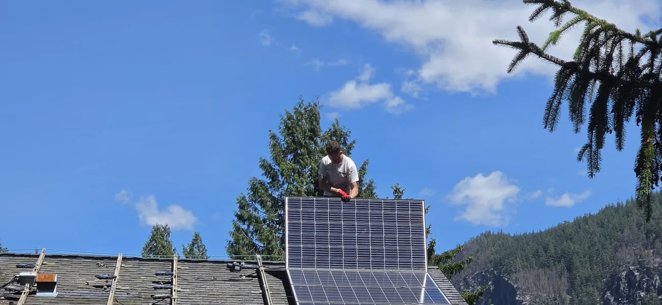 An installer lifting a solar panel onto a roof
