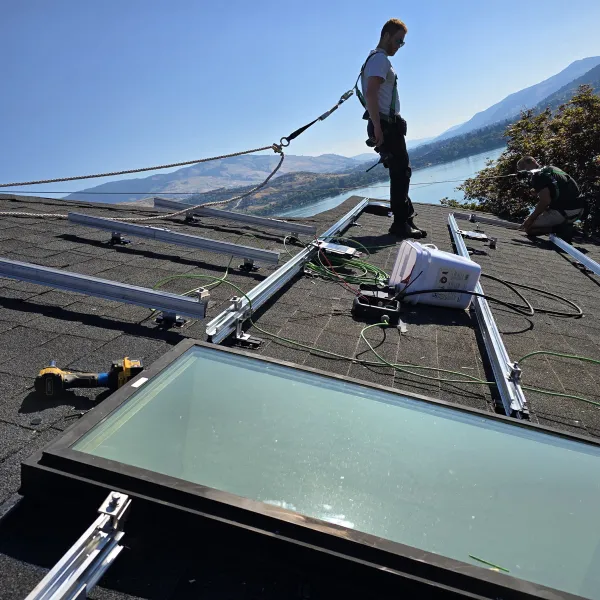 An installer roped in on a roof, working beside the rails